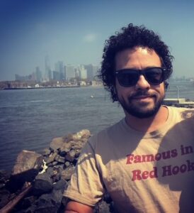 Headshot of Luis in front of a city waterfront 